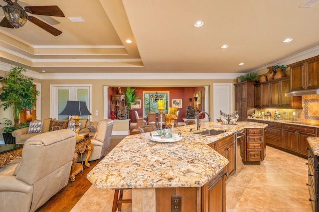 kitchen with sink, ceiling fan, an island with sink, and crown molding