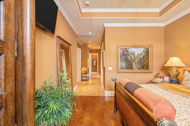 bedroom with hardwood / wood-style flooring, ornamental molding, and a raised ceiling