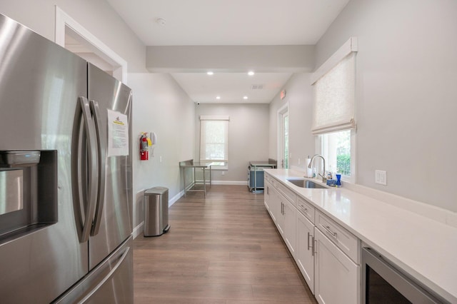 kitchen with plenty of natural light, stainless steel fridge, hardwood / wood-style flooring, and white cabinetry