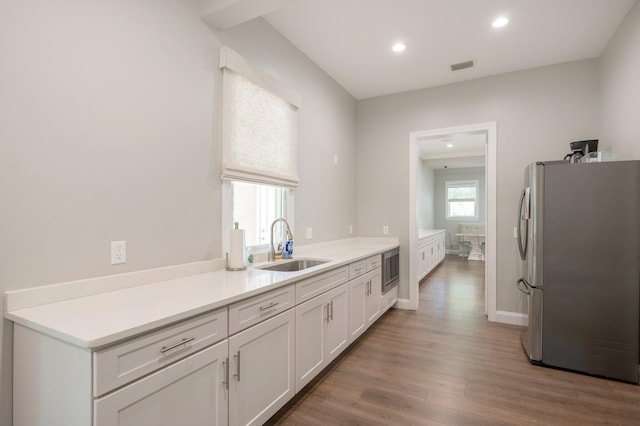 kitchen featuring hardwood / wood-style flooring, appliances with stainless steel finishes, white cabinets, and sink