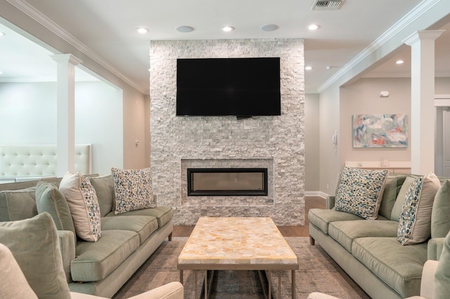 living room with hardwood / wood-style floors, ornate columns, crown molding, and a stone fireplace