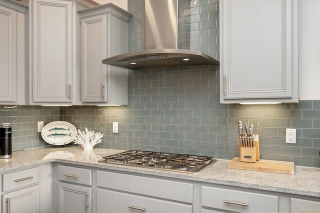 kitchen featuring wall chimney range hood, backsplash, and stainless steel gas stovetop