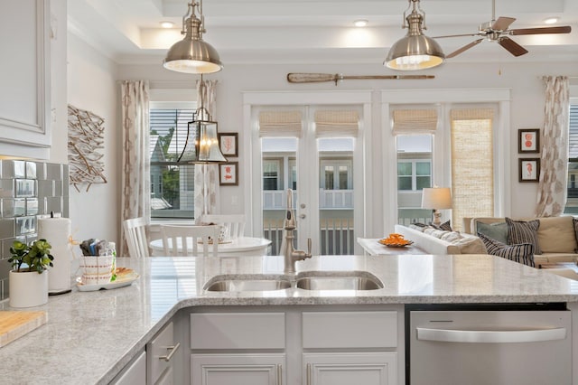 kitchen with a tray ceiling, dishwasher, and decorative light fixtures