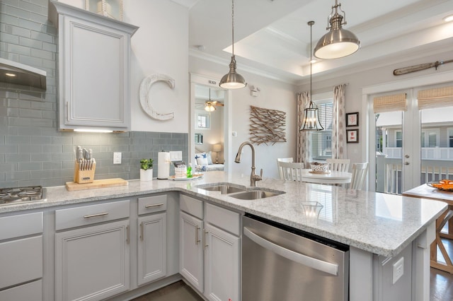 kitchen featuring sink, dishwasher, a raised ceiling, hanging light fixtures, and light stone countertops