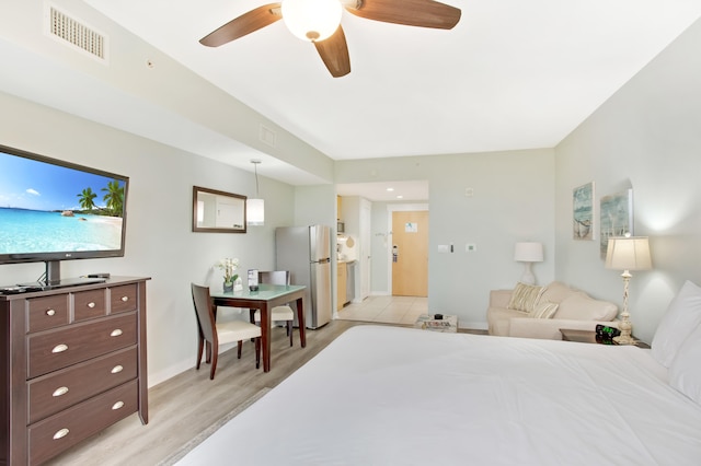 bedroom featuring stainless steel fridge and light hardwood / wood-style flooring