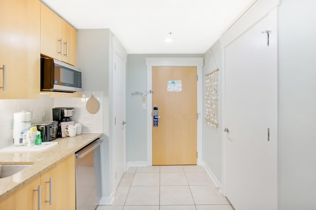 kitchen with appliances with stainless steel finishes, decorative backsplash, light tile patterned floors, light stone countertops, and light brown cabinets