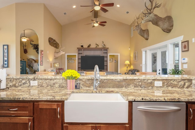 kitchen featuring dishwasher, sink, high vaulted ceiling, and light stone counters