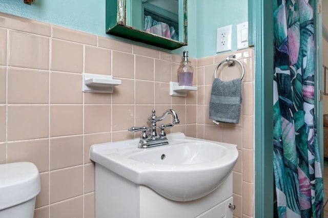 bathroom featuring tasteful backsplash, toilet, oversized vanity, and tile walls