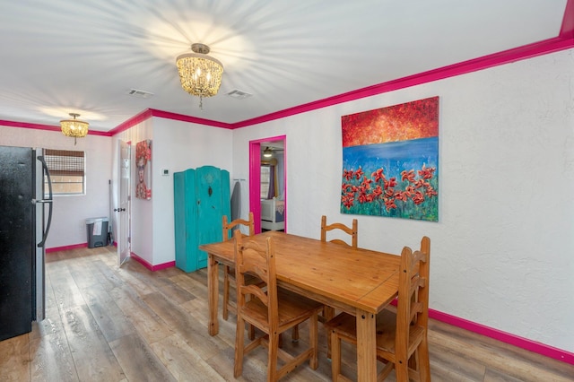 dining space with an inviting chandelier, wood-type flooring, and crown molding