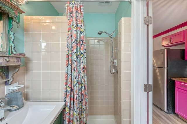 bathroom with tile walls, curtained shower, crown molding, wood-type flooring, and vanity