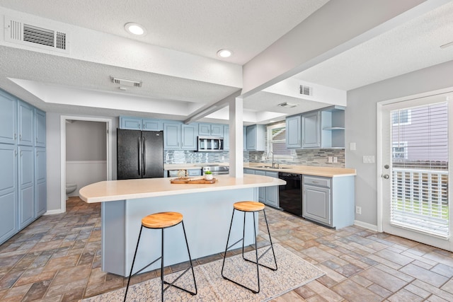 kitchen featuring black appliances, tasteful backsplash, a breakfast bar area, and a textured ceiling