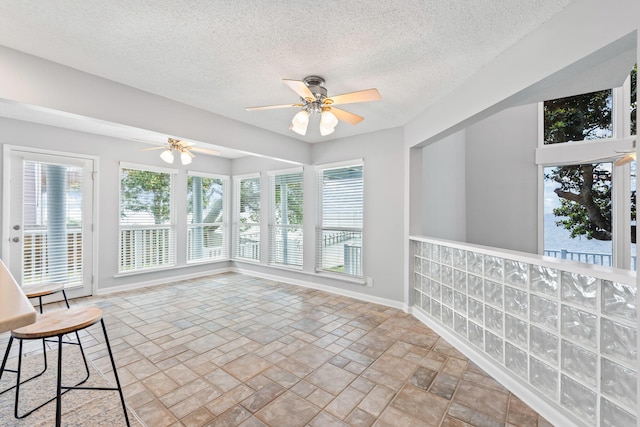 unfurnished sunroom with ceiling fan