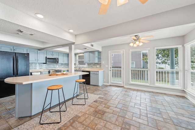 kitchen with a kitchen breakfast bar, decorative backsplash, ceiling fan, and black appliances