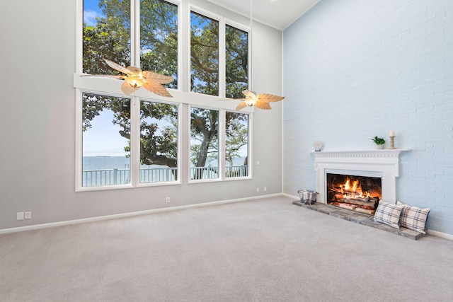 unfurnished living room with a water view, a towering ceiling, plenty of natural light, and carpet floors