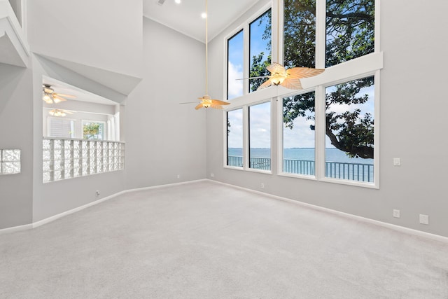 spare room with carpet flooring, a water view, and a high ceiling