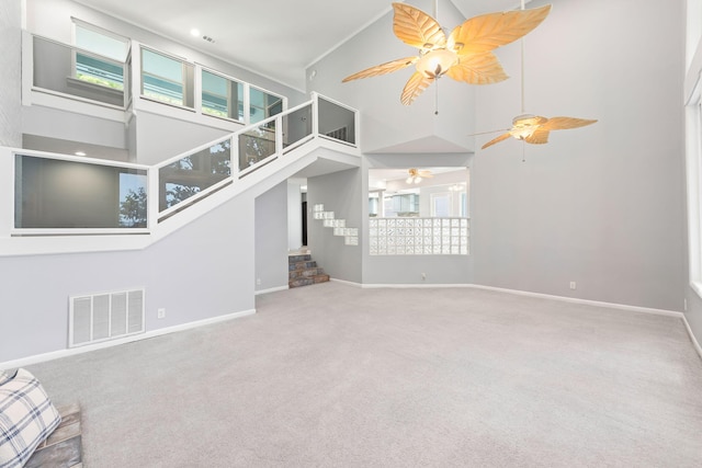 unfurnished living room featuring carpet, high vaulted ceiling, and a healthy amount of sunlight