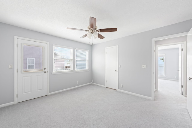 unfurnished bedroom featuring a textured ceiling, light colored carpet, and ceiling fan