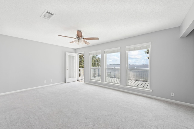 spare room with light carpet, ceiling fan, and a textured ceiling