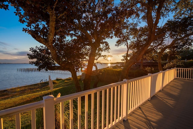 deck at dusk featuring a water view