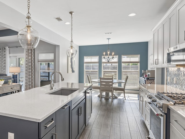 kitchen featuring sink, dark hardwood / wood-style flooring, hanging light fixtures, stainless steel appliances, and an island with sink