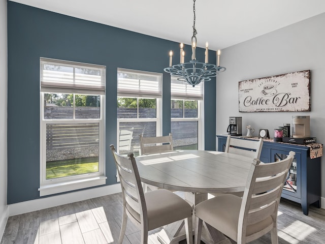 dining room with wood-type flooring, plenty of natural light, and a notable chandelier