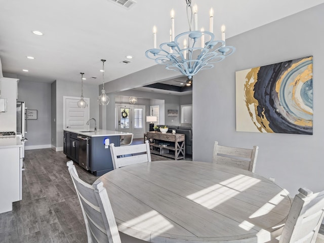 dining area with an inviting chandelier, dark hardwood / wood-style flooring, sink, and a tray ceiling