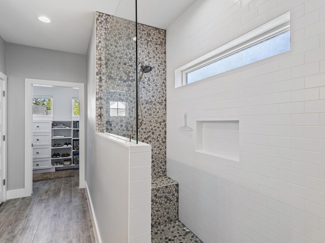 bathroom featuring hardwood / wood-style floors, tile walls, and a tile shower