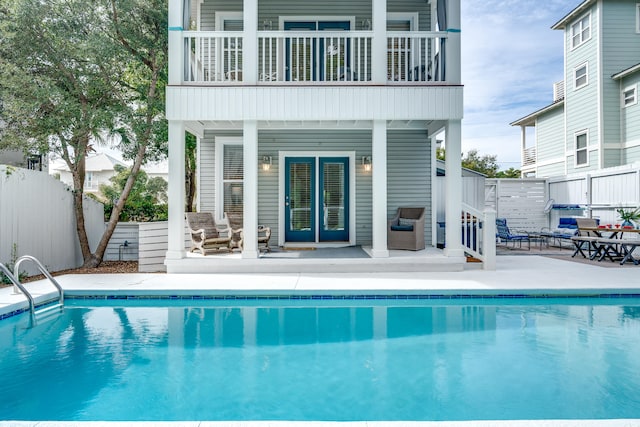 back of house featuring an outdoor living space, a patio, a balcony, and a fenced in pool