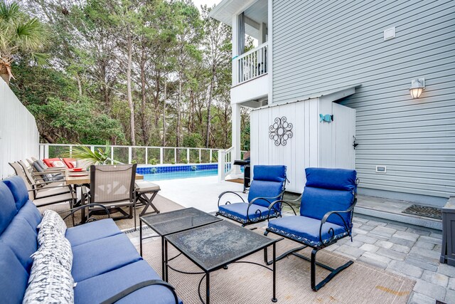 view of patio featuring a fenced in pool, an outdoor living space, and a balcony