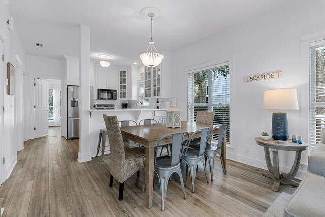 dining room with light hardwood / wood-style floors and a notable chandelier