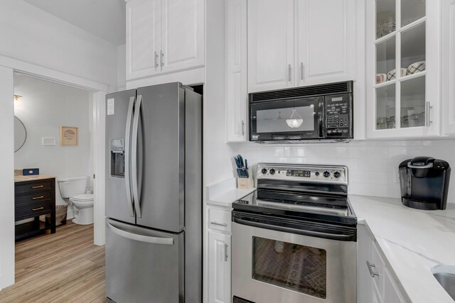 kitchen featuring light stone countertops, appliances with stainless steel finishes, light wood-type flooring, and white cabinetry