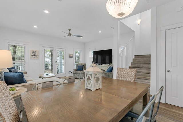 dining space with french doors, ceiling fan with notable chandelier, and hardwood / wood-style flooring