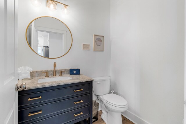 bathroom with hardwood / wood-style floors, vanity, and toilet