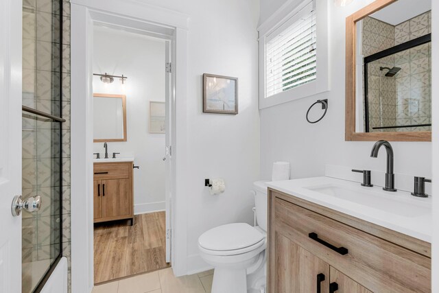 bathroom featuring tile patterned floors, vanity, toilet, and walk in shower