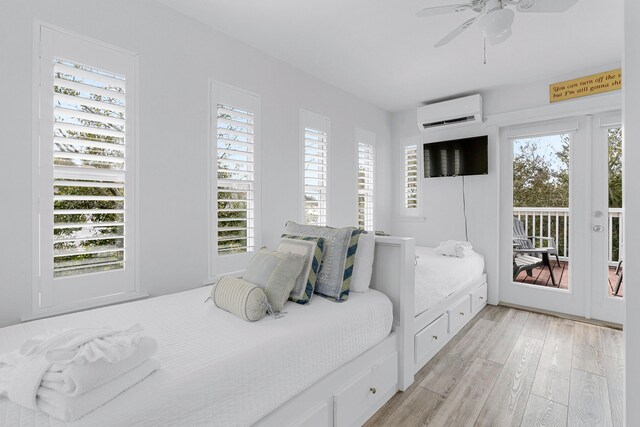 bedroom with a wall mounted AC, light wood-type flooring, access to exterior, and ceiling fan