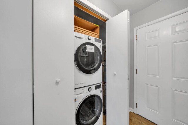 washroom featuring hardwood / wood-style floors and stacked washer and dryer