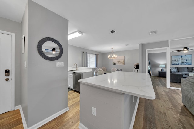 kitchen featuring ceiling fan with notable chandelier, light hardwood / wood-style flooring, and a center island