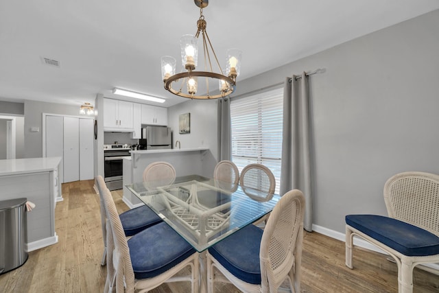 dining space featuring a notable chandelier and light wood-type flooring