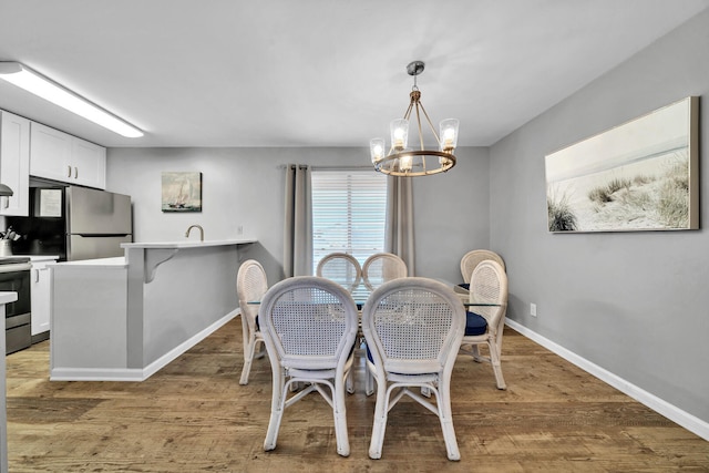 dining room with a notable chandelier, light wood-type flooring, and sink