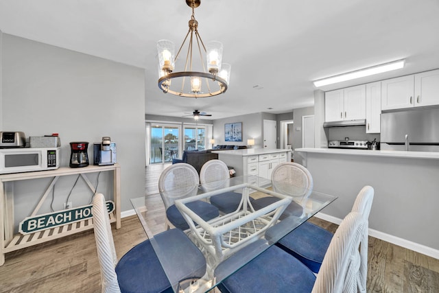 dining space with ceiling fan with notable chandelier and wood-type flooring