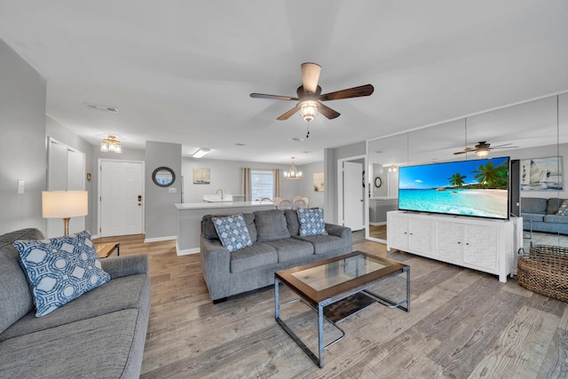 living room featuring ceiling fan with notable chandelier and hardwood / wood-style flooring