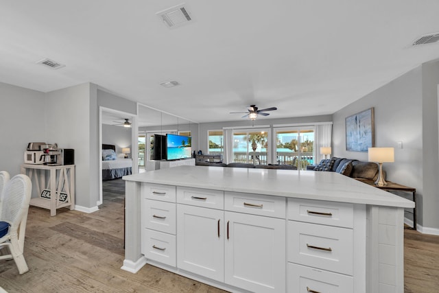 kitchen featuring a kitchen island, ceiling fan, white cabinetry, and light hardwood / wood-style flooring