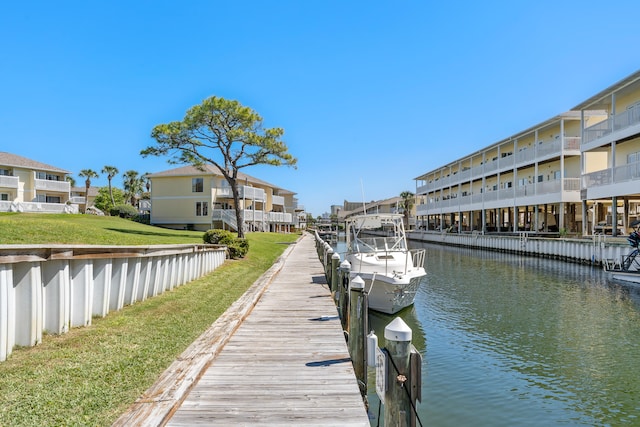 dock area featuring a water view, a balcony, and a lawn