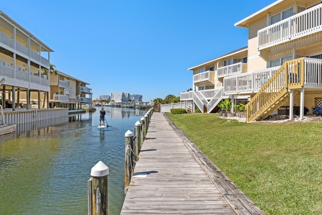 view of dock featuring a water view, a yard, and a balcony