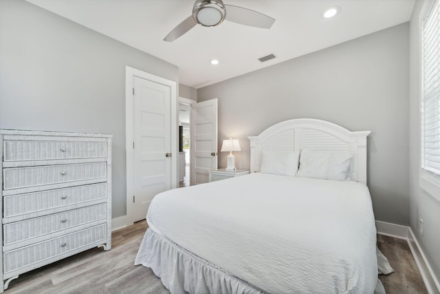 bedroom featuring ceiling fan, hardwood / wood-style flooring, and multiple windows