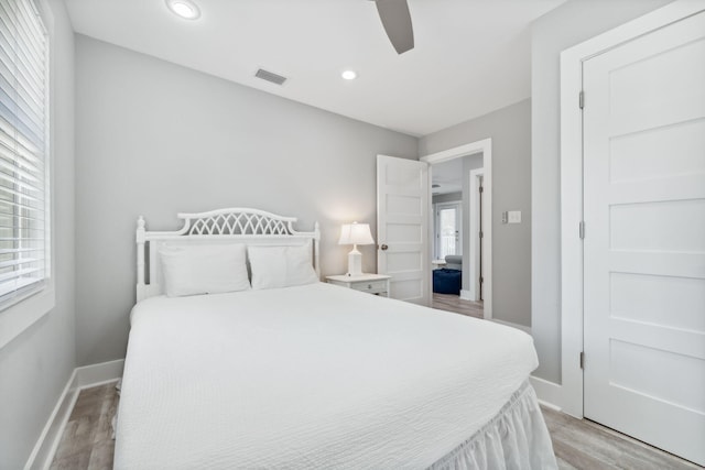 bedroom with light hardwood / wood-style floors, ceiling fan, and multiple windows