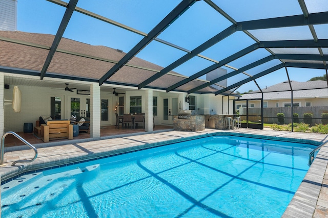 view of swimming pool with a patio, a lanai, ceiling fan, and an outdoor kitchen