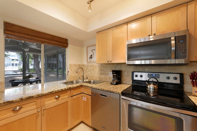 kitchen with tasteful backsplash, stainless steel appliances, sink, and light stone counters