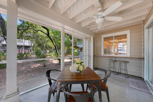 sunroom / solarium featuring ceiling fan and beamed ceiling