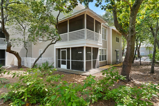 back of property featuring a sunroom and a balcony